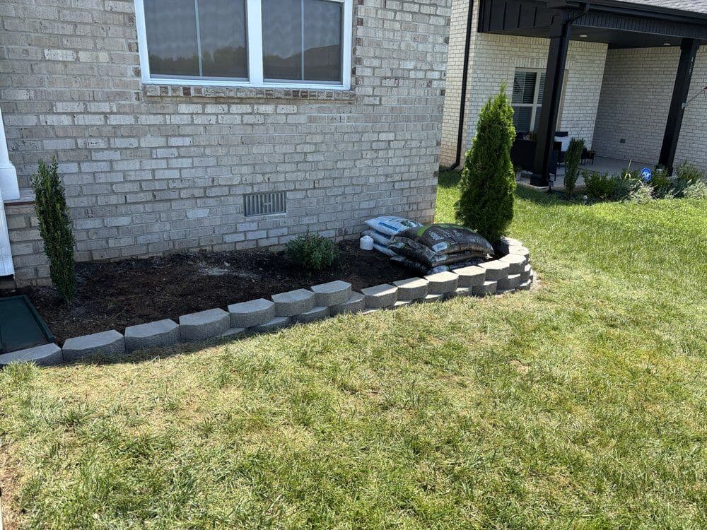New block retaining wall and flower bed against a brick Clarksville home